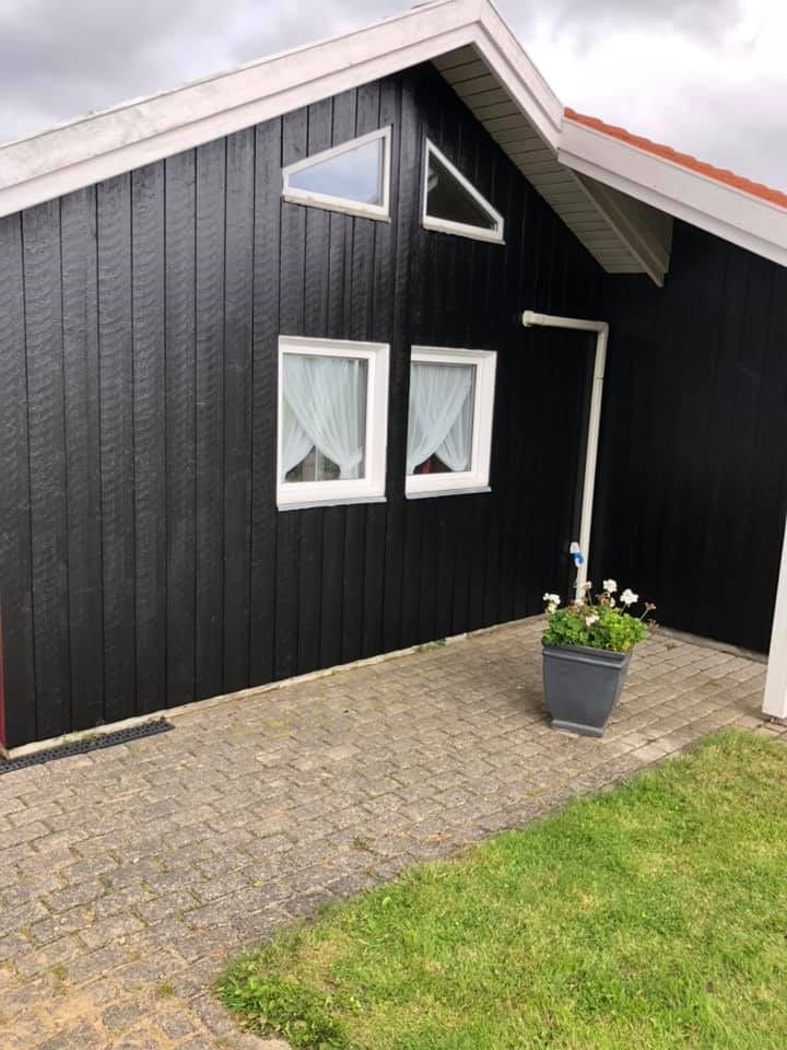 Sort træhus med hvide vinduer og blomsterkrukke