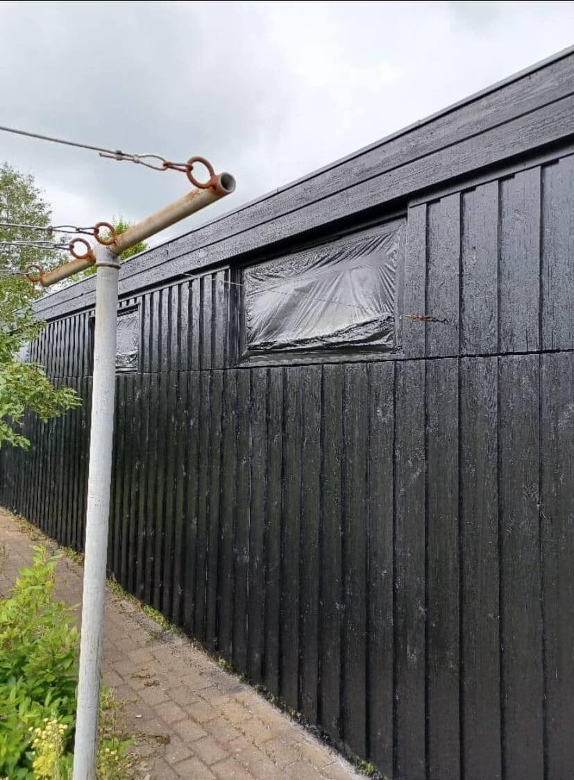 Sort træbygning med plastikdækkede vinduer