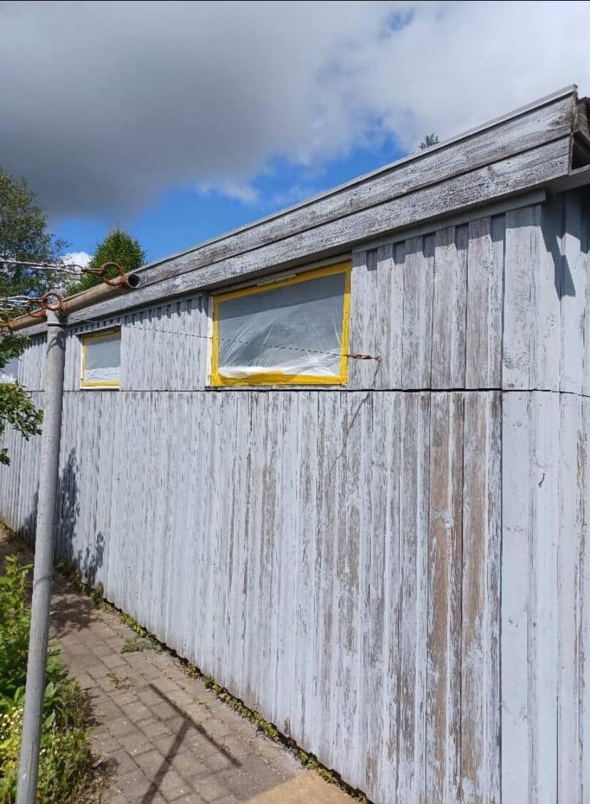 Trævæg på ældre bygning med falmet maling