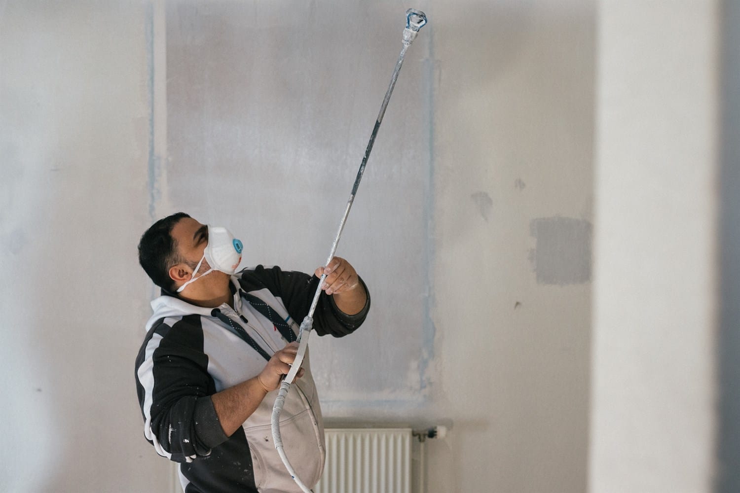 Maleren sprøjtemaler væg i lejlighed