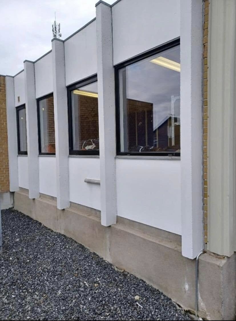 Hvid facade med sorte vinduer på bygning